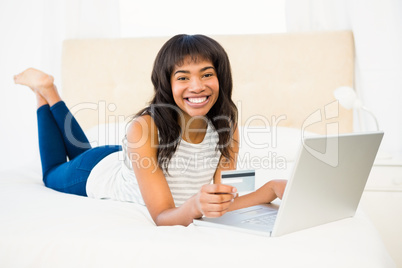 Casual smiling woman using laptop while holding a card