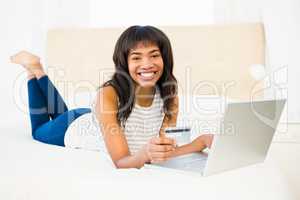 Casual smiling woman using laptop while holding a card