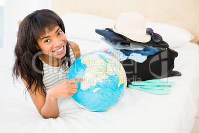 Casual smiling woman touching globe on the bed