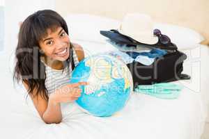 Casual smiling woman touching globe on the bed