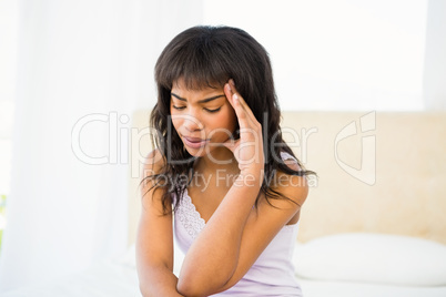 Casual unhappy woman sitting on her bed