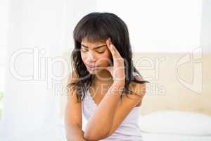 Casual unhappy woman sitting on her bed