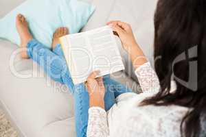Over shoulder view of a casual woman reading a book