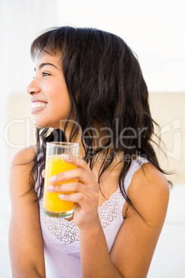 Casual smiling woman holding a glass of orange juice