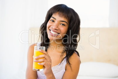 Casual smiling woman holding a glass of orange juice