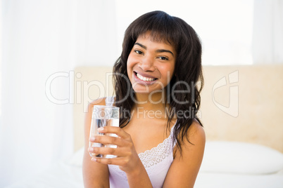 Casual smiling woman holding a glass of water