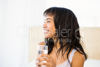 Casual smiling woman holding a glass of water