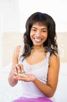 Casual smiling woman holding a box of pills
