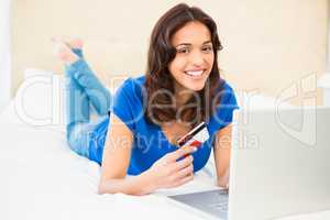 Casual smiling woman using laptop while holding a card