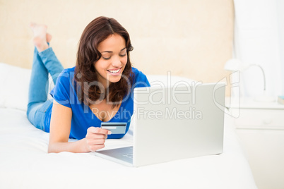 Casual smiling woman using laptop while holding a card