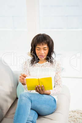 Casual smiling woman reading a yellow book