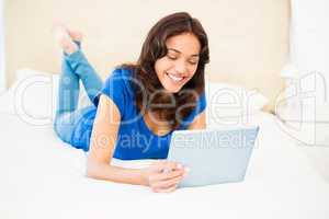 Casual smiling woman using laptop on the bed