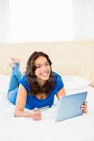 Casual smiling woman using laptop while holding a card