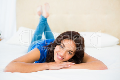 Smiling woman using smartphone while lying on bed