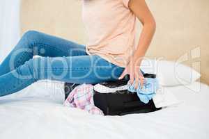 Woman sitting on her overfull suitcase