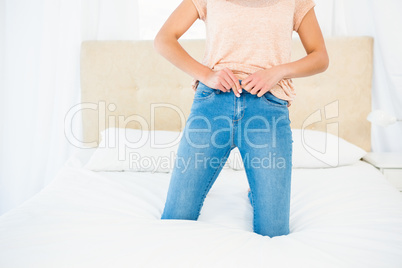 Casual smiling woman trying to close her jeans