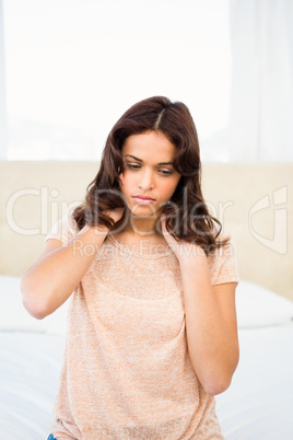 Casual woman with neck pain sitting on her bed