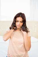Casual woman with neck pain sitting on her bed
