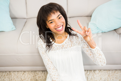 Casual smiling woman gesturing peace sign