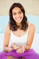 Casual smiling woman holding a box of pills