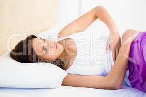 Woman lying on her bed with a belly pain