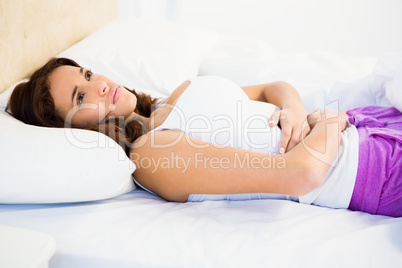 Woman lying on her bed with a belly pain