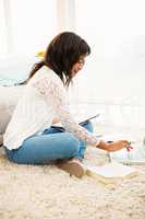 Casual smiling woman writing notes while using her laptop