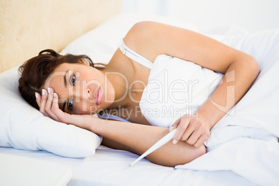 Woman holding her head and a thermometer