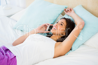 Pretty woman having a phone call while lying on the bed