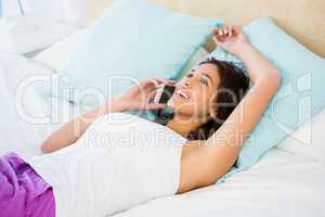 Pretty woman having a phone call while lying on the bed