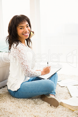 Smiling woman writing notes while looking the camera