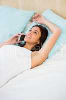 Pretty woman having a phone call while lying on the bed