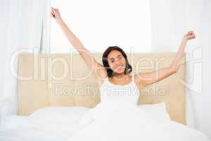 Pretty woman waking up with outstretched arms