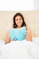 Pretty woman reading book in her bed