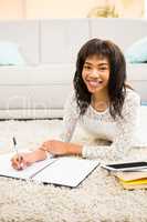 Smiling woman writing notes while looking the camera