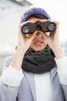 Woman with winter clothes looking into binoculars
