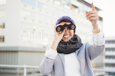 Smiling woman with binoculars pointing up