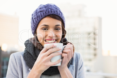 Smiling woman drinking hot beverage