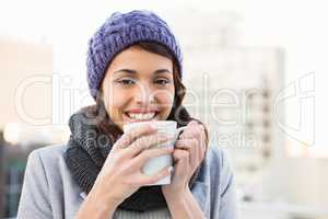 Smiling woman drinking hot beverage