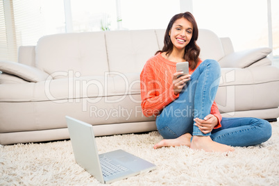 Smiling woman using smartphone while sitting on floor