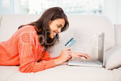 Smiling woman using laptop while holding a credit card