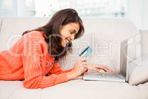 Smiling woman using laptop while holding a credit card