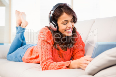 Smiling woman listening music while using her tablet