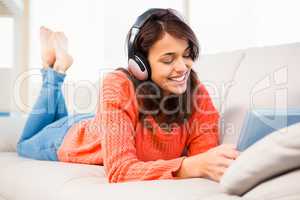 Smiling woman listening music while using her tablet