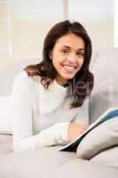 Pretty brunette reading magazine on the couch