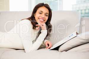 Pretty brunette reading magazine on the couch