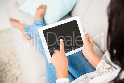 Over shoulder view of a woman using tablet on the couch