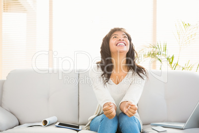 Woman raising her hands up on the couch with laptop