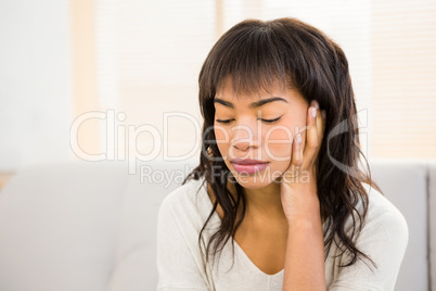 Stressed woman holding her head on couch