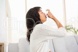 Woman using her inhaler on the couch
